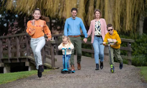 Vader en moeder wandelen in het park met drie kinderen, en de kinderen zijn aan het steppen